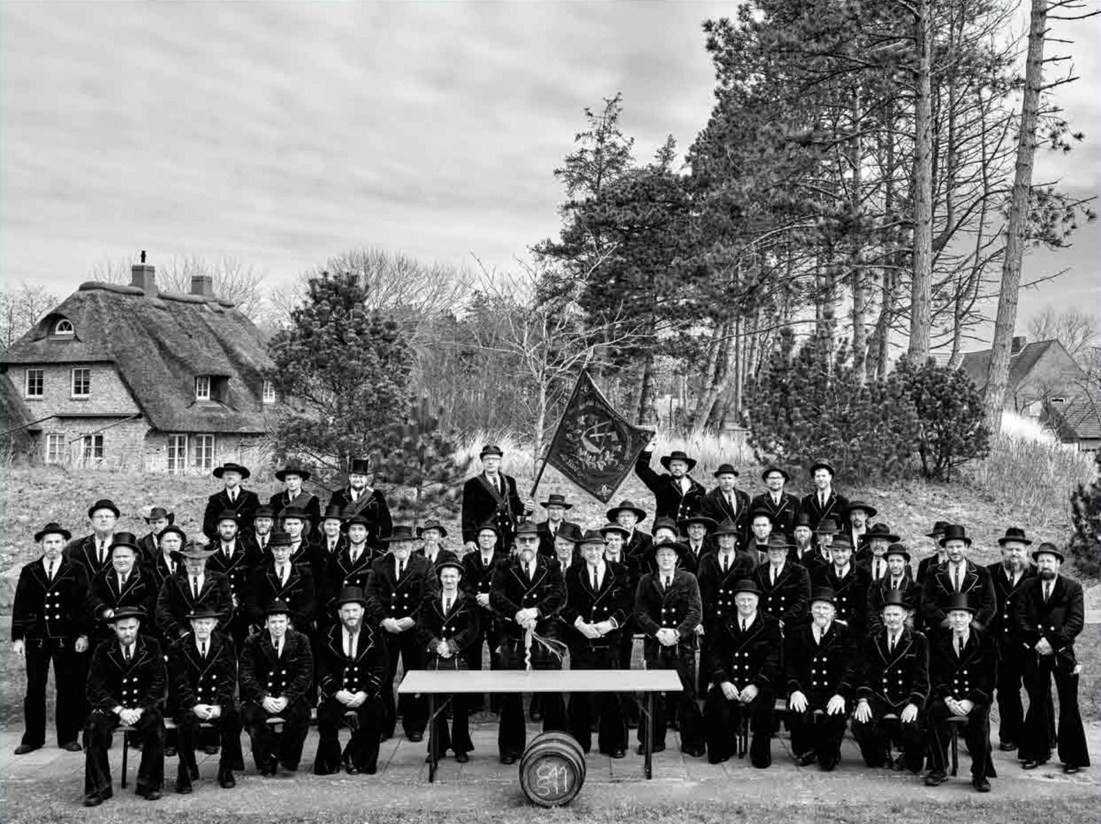 Gruppenbild der Delegierten beim 32. Kongress in St. Peter-Ording 2026, in Kluft mit Fahne vor einem Reetdachhaus