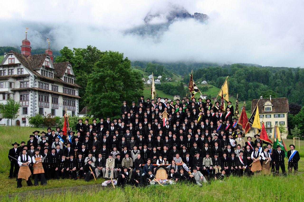 Gruppenbild mit Fahnen vor Bergkulisse in Schwyz